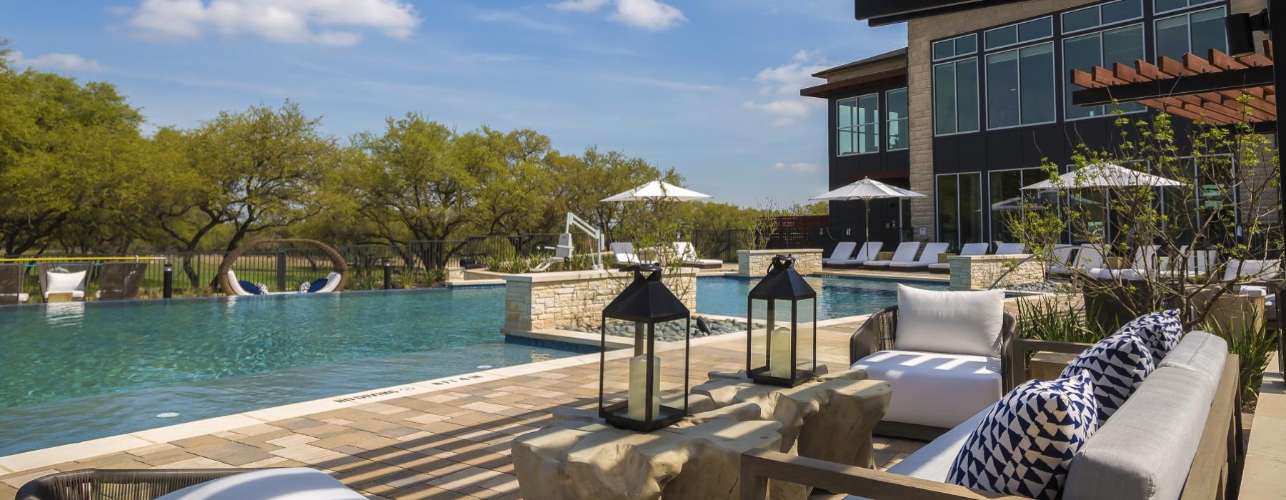 a pool with chairs and a building by it